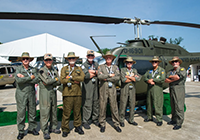 Vietnam veteran helicopter pilotes lined up in front of a huey on Camp Legacy.
